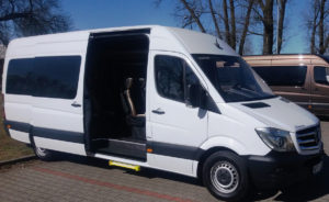 Biały bus z firmy przewozu osób czeka na klientów na parkingu w Warszawie